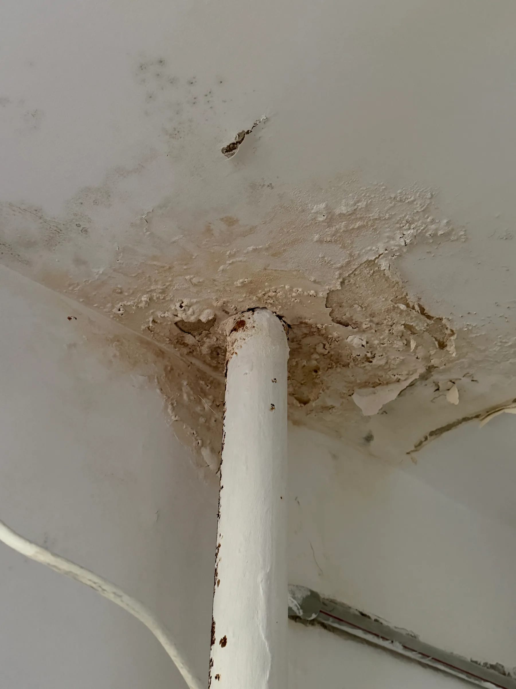 Zawilgocony i odspojony tynk na suficie przy przejściu instalacyjnym