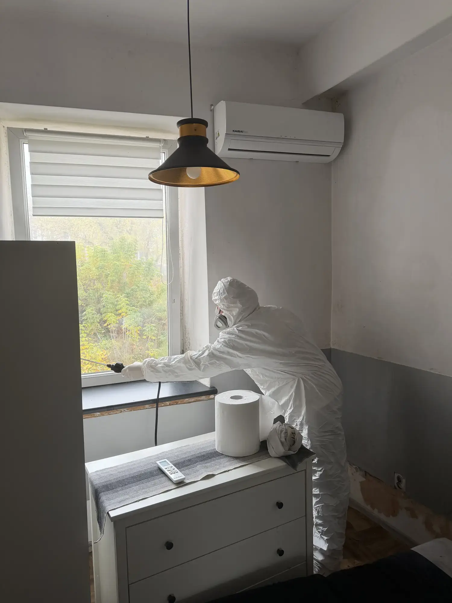 Technik sięga lancą do bocznej części okna nad parapetem