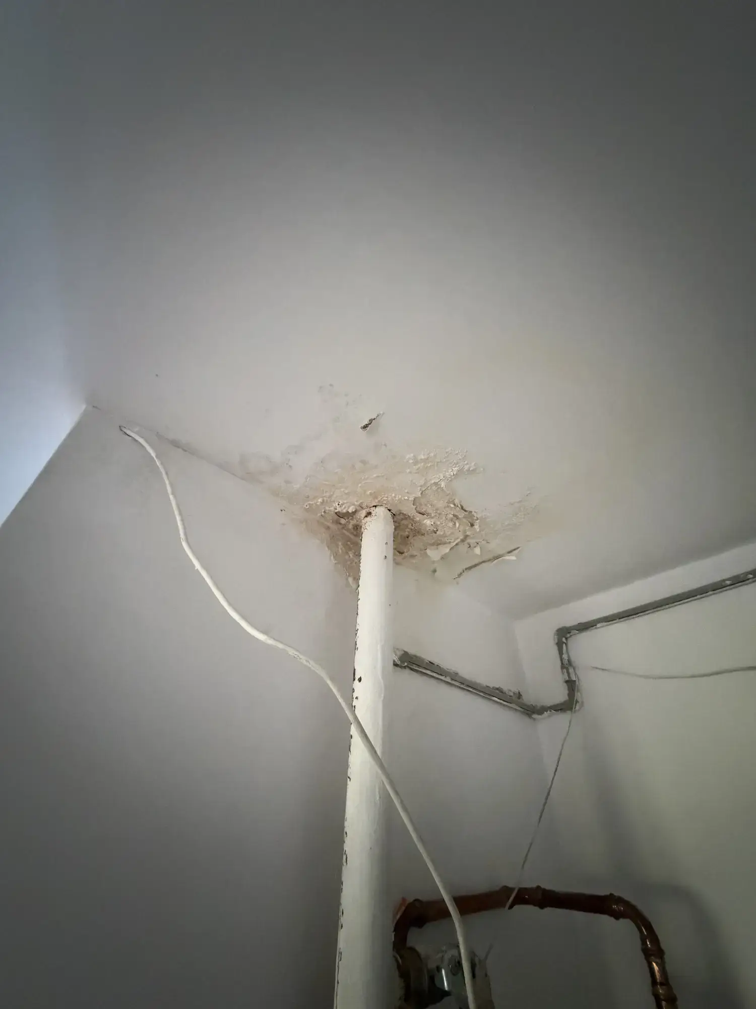 Widok pionu instalacyjnego i zniszczonego tynku przy suficie