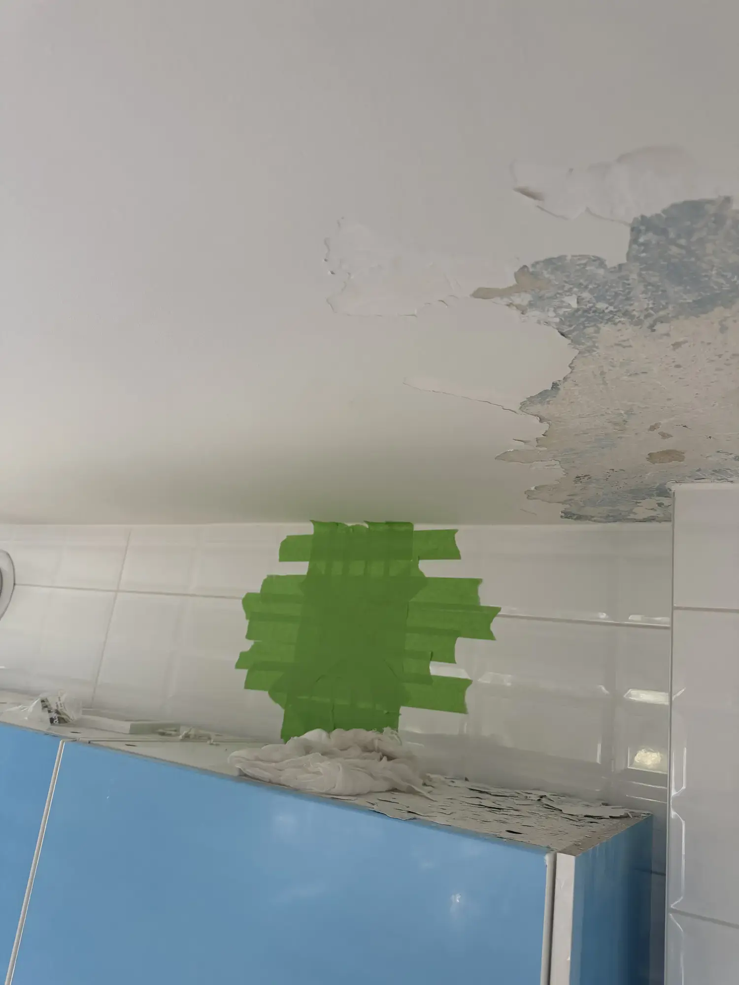 Uszkodzenia sufitu nad ścianą wyłożoną płytkami